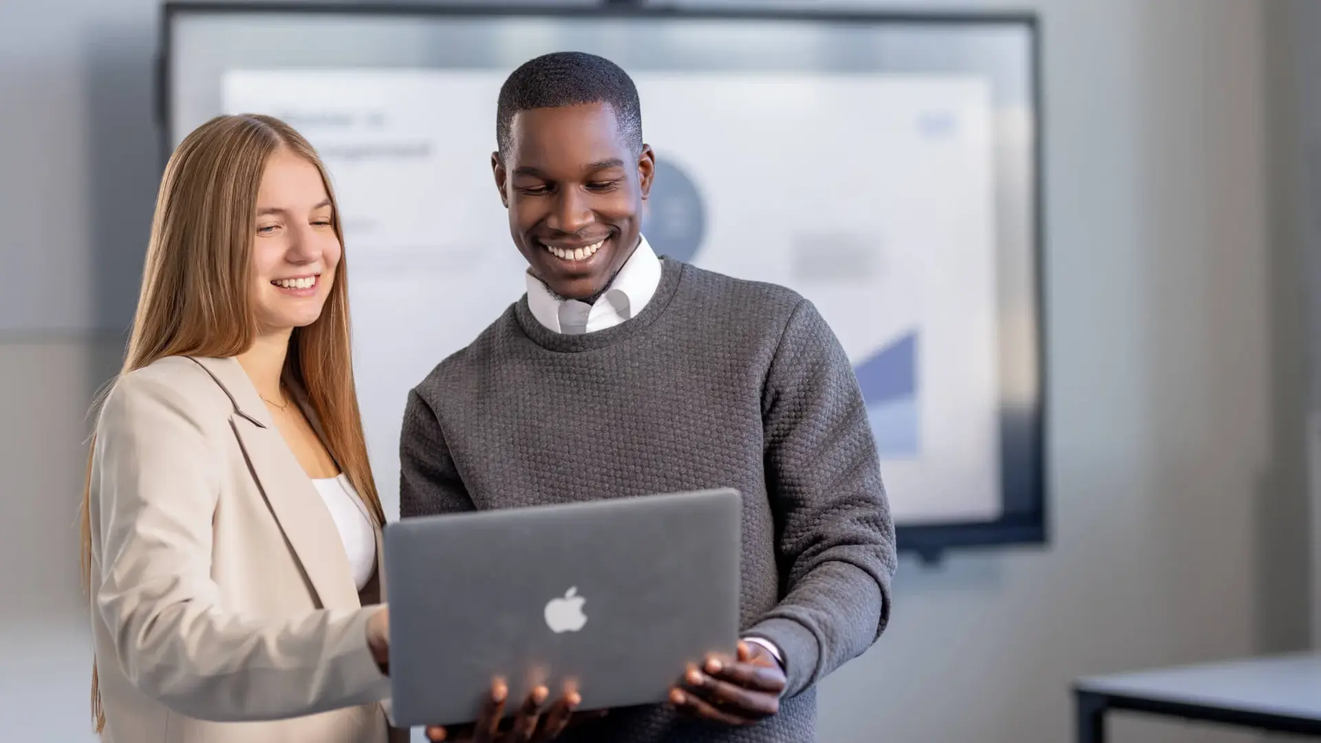 Man and woman discussing a project on a laptop in a modern office space