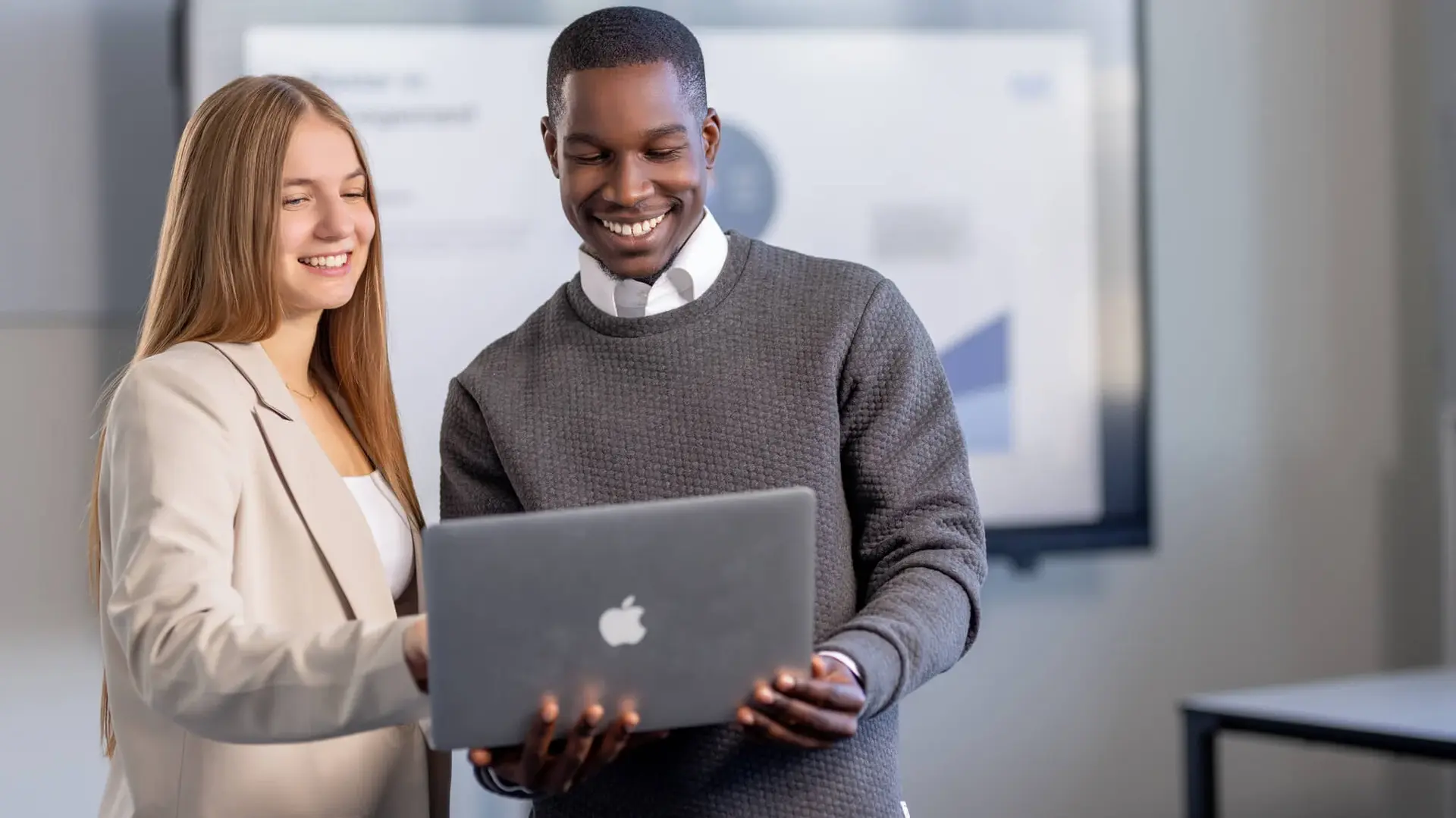 Mann und Frau besprechen ein Projekt an einem Laptop in einem modernen Büroraum