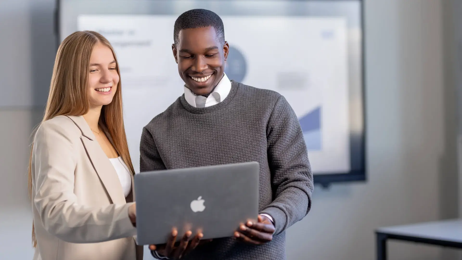 Mann und Frau besprechen ein Projekt an einem Laptop in einem modernen Büroraum