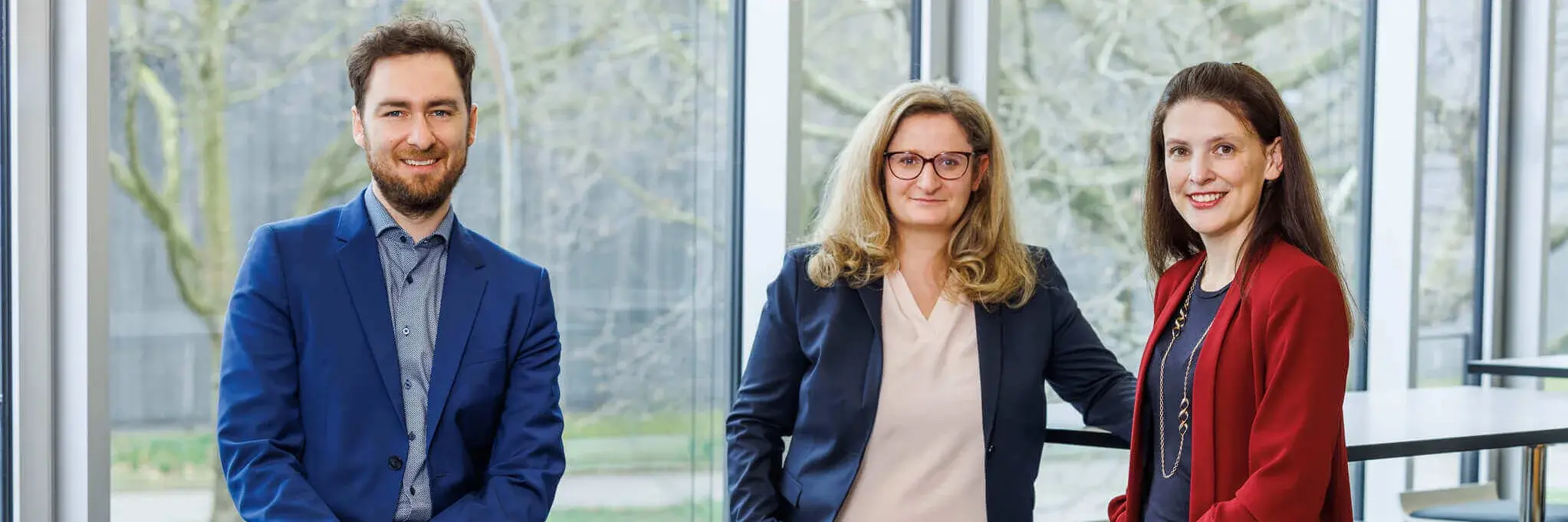 "Three professors posing by window