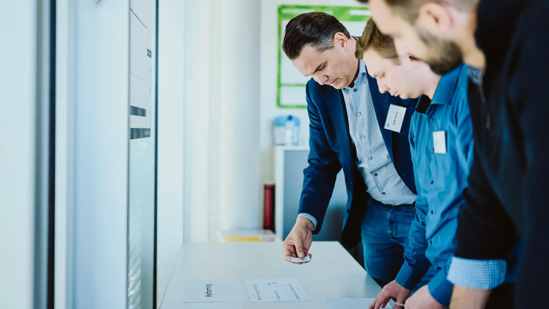 Three men standing in front of a desk and brainstorming during a working