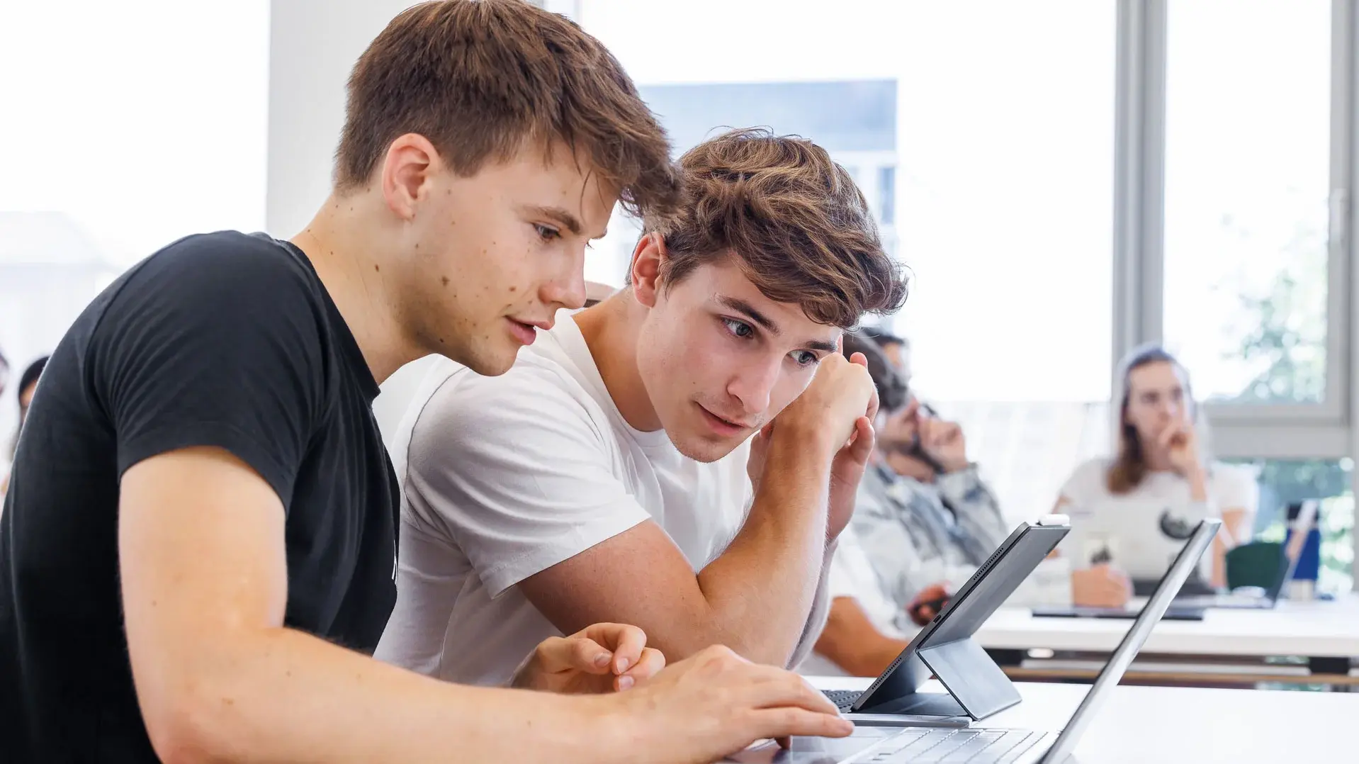 [Translate to German:] Two students looking into a laptop