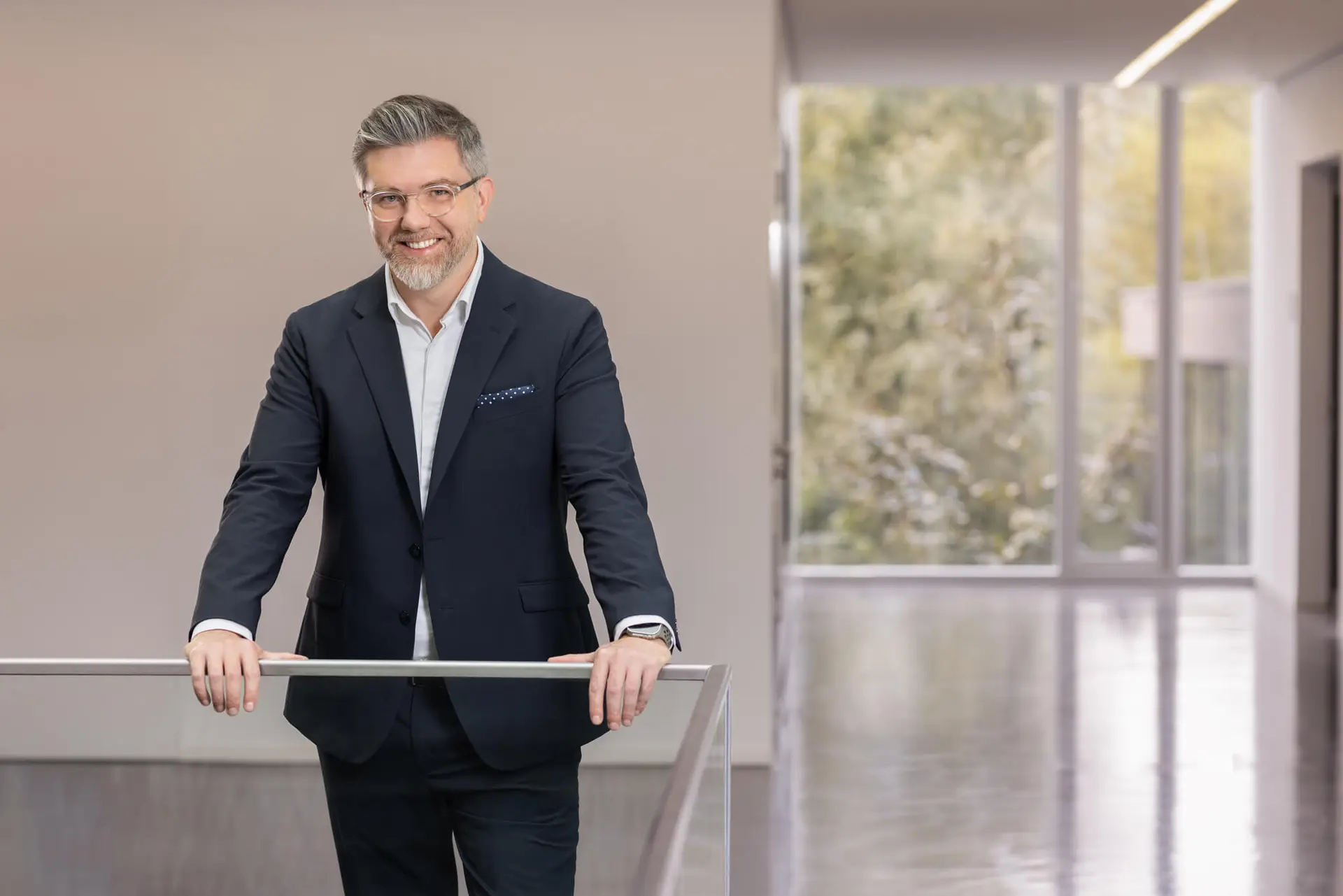 Prof. Dr. Ali Sunyaev leaning against a glass railiing