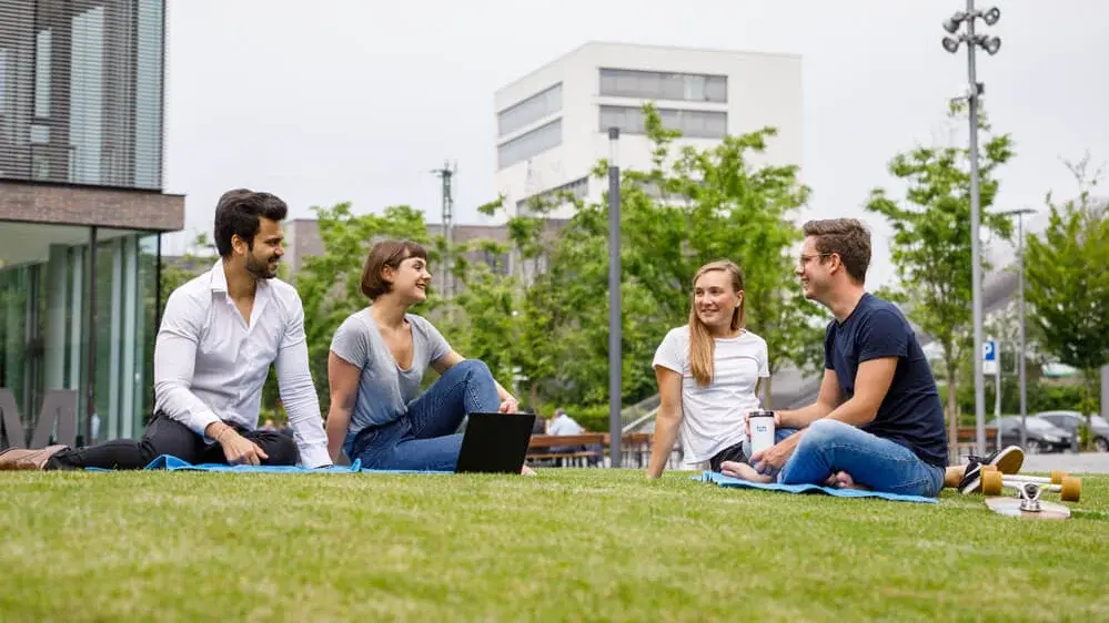 Studenten sitzen auf dem Rasen des Campus