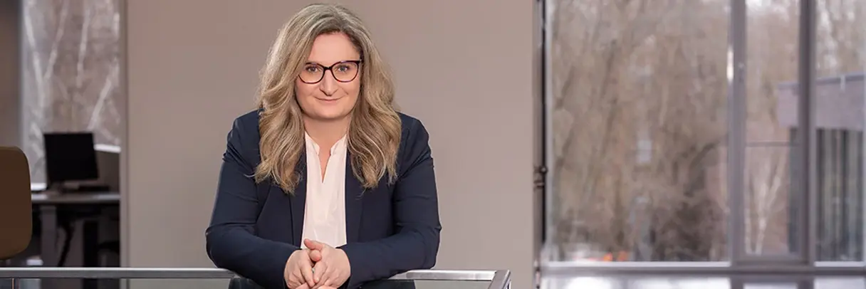 Eine Frau im Anzug lehnt sich gegen ein Geländer