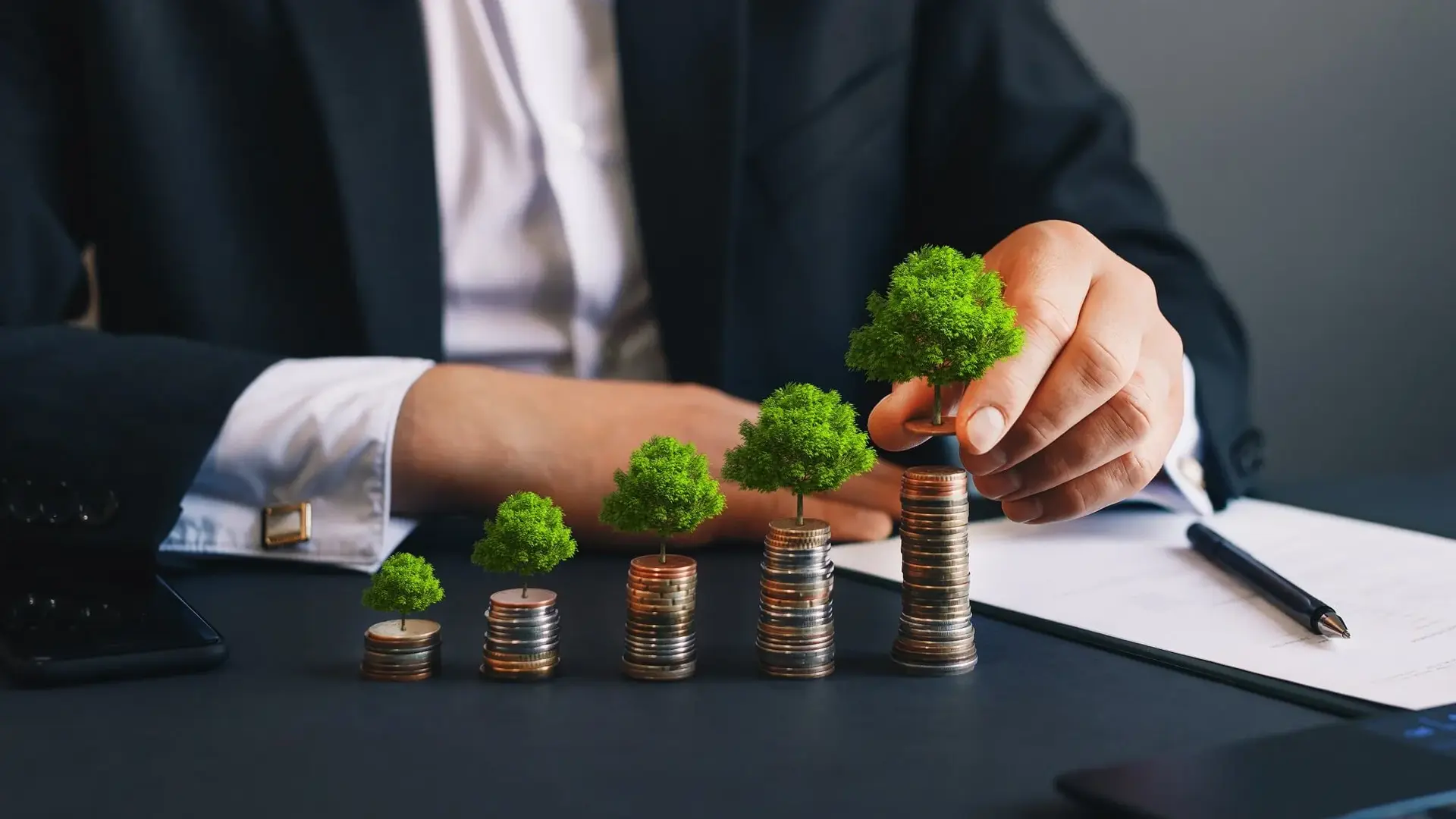 [Translate to German:] Stacked coins with plastic trees on them