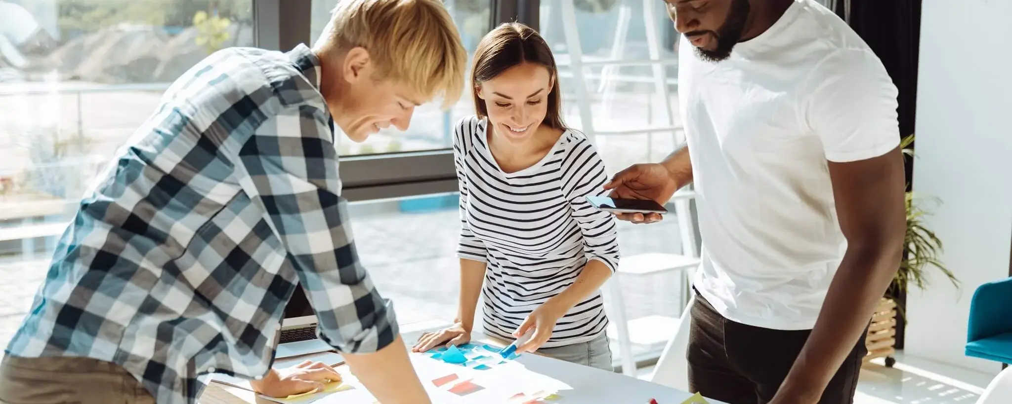 3 Personen planen ein Projekt an einem Tisch