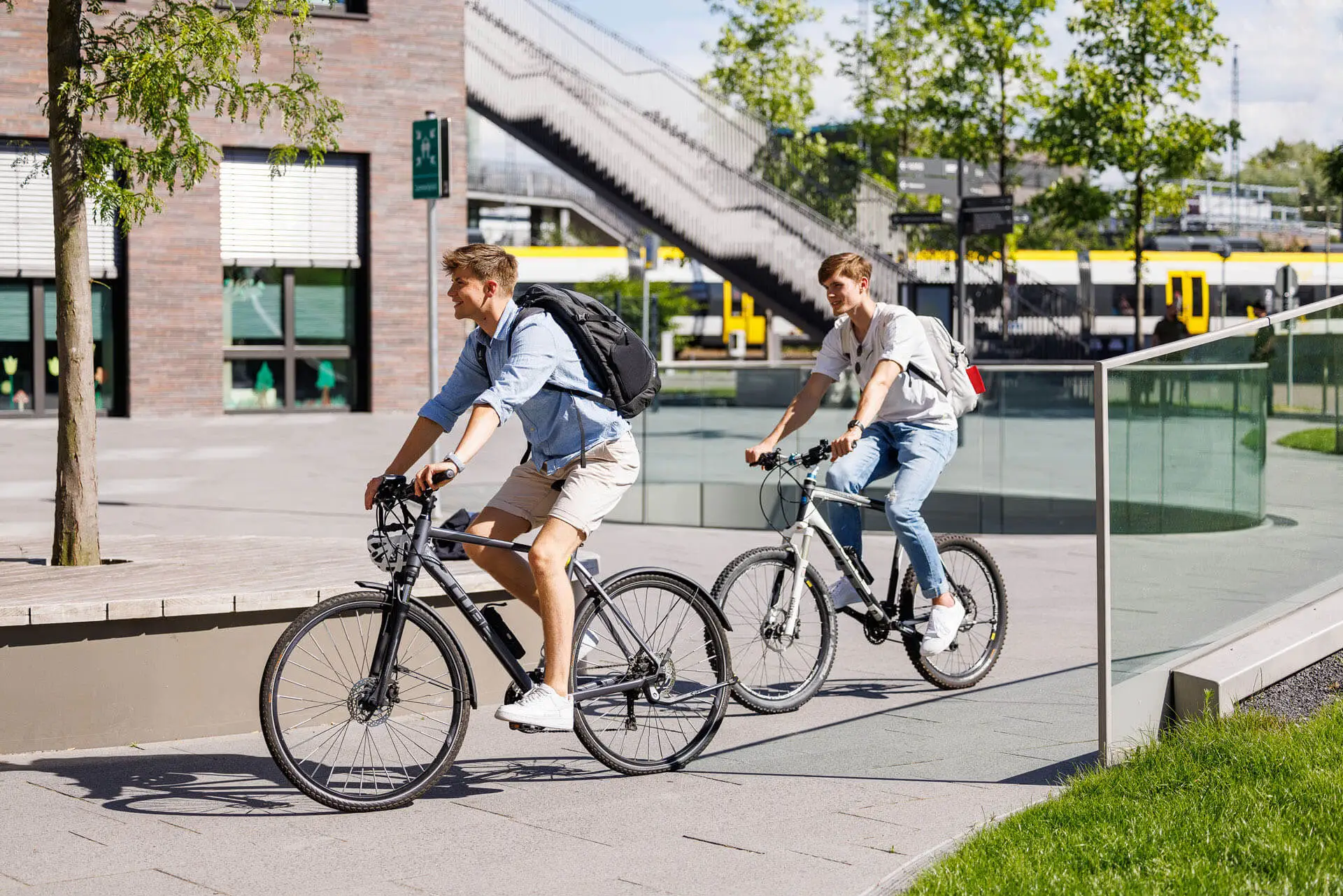 Zwei Personen fahren auf dem Campus Fahrrad