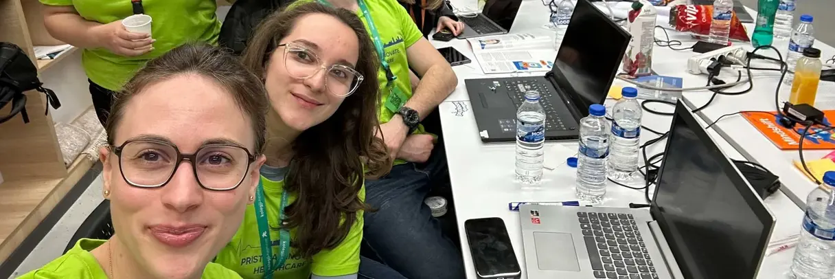 [Translate to German:] A group of eight people, wearing matching green shirts, pose around a table cluttered with laptops, water bottles, and snacks. They appear cheerful and are inside a room with a Sentry Cyber Solutions logo on the wall.