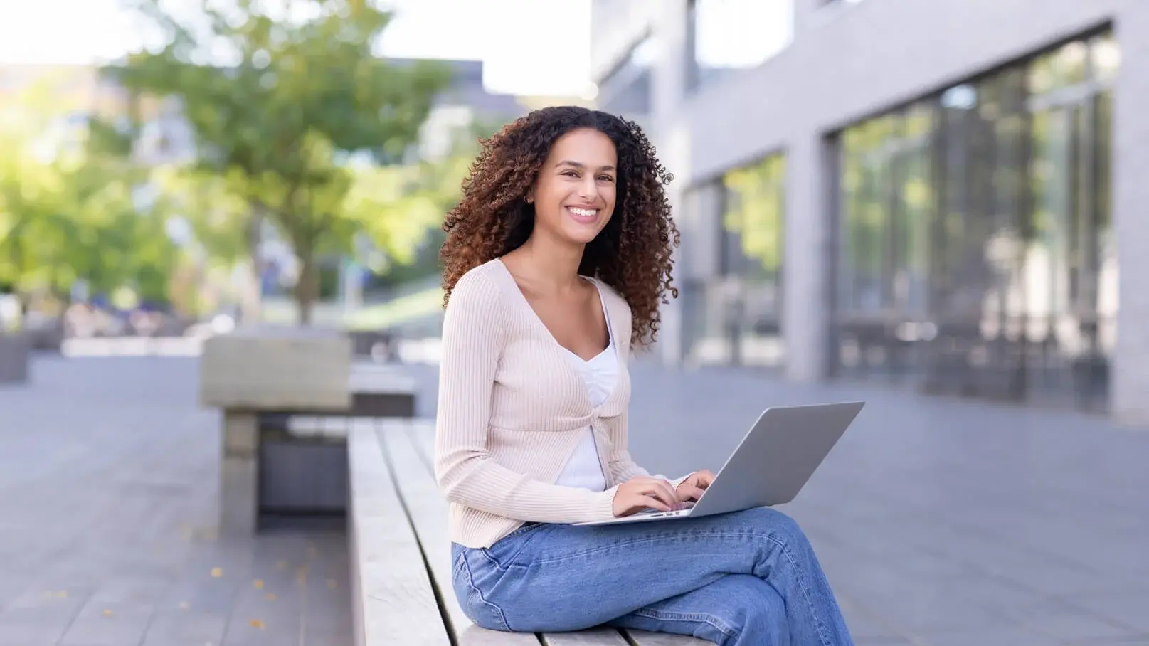 Ein Student arbeitet an einem Laptop draußen auf dem Campus