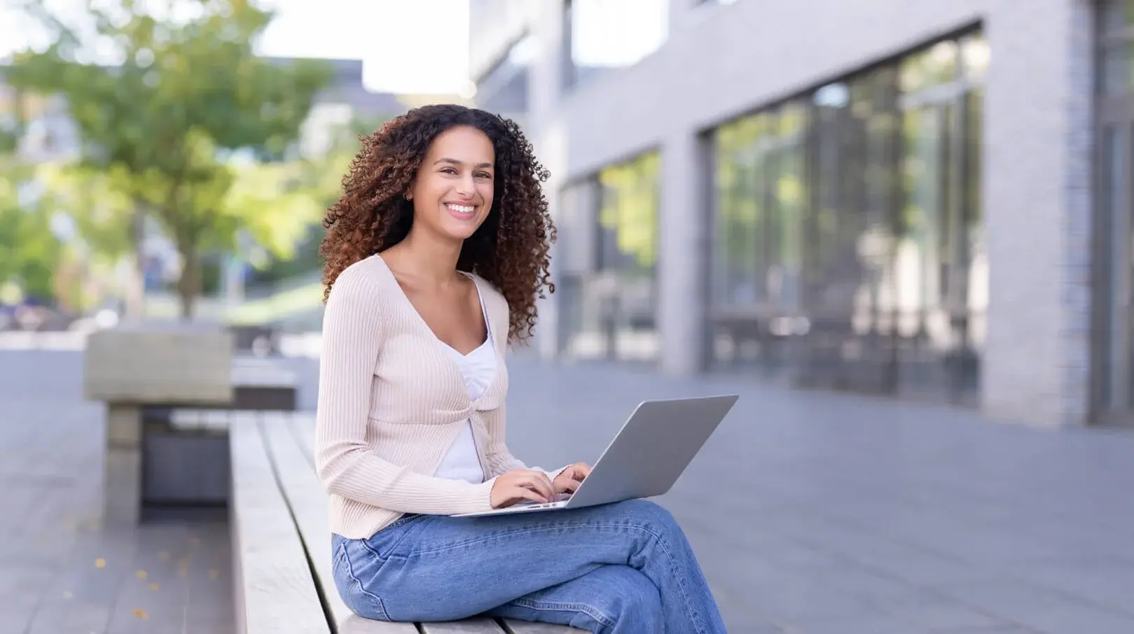 Ein Student arbeitet an einem Laptop draußen auf dem Campus