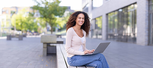 Student working on a laptop outside on campus