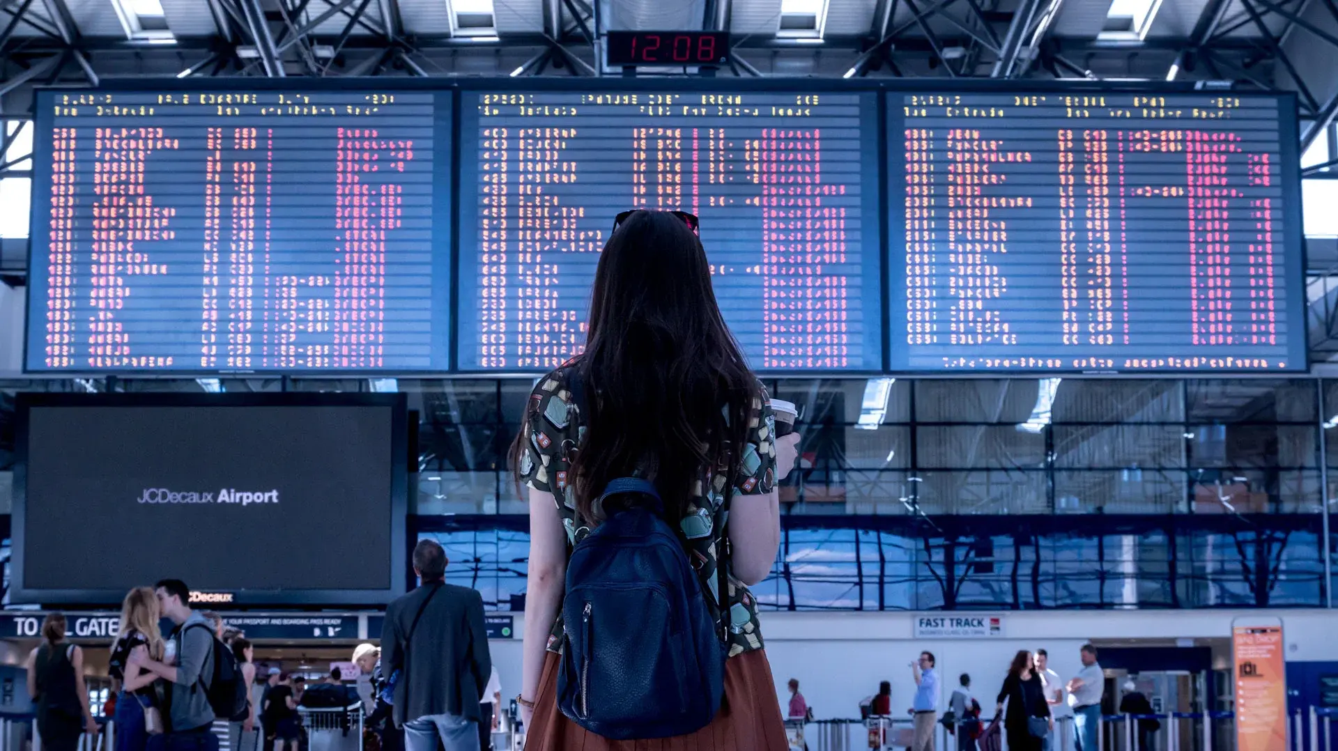 Eine junge Frau steht vor der Abflugtafel auf einem Flughafen